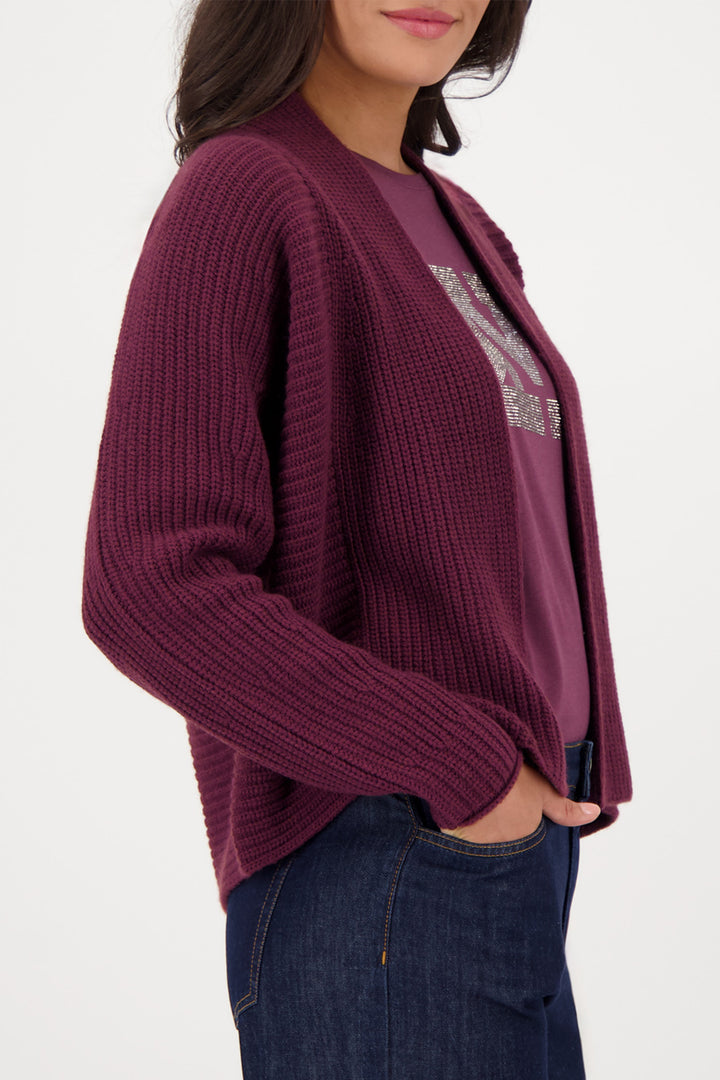 Person wearing a maroon cardigan with a white background