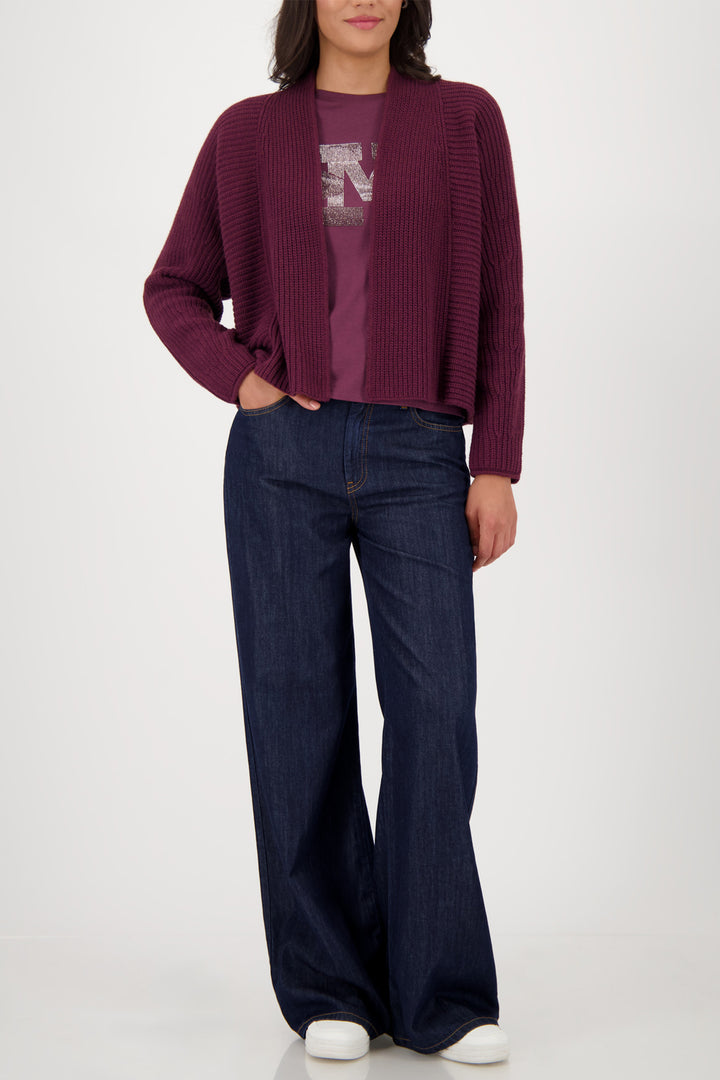 Person wearing a burgundy sweater and blue jeans on a white background