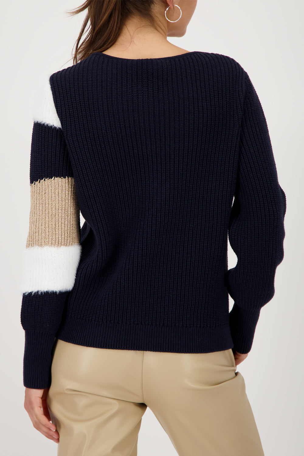Navy sweater with beige and white sleeve design worn by a person on a white background
