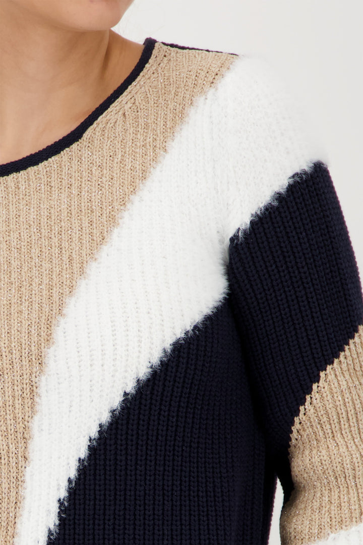 Close-up of a sweater with a geometric pattern in beige, white, and navy on a white background.