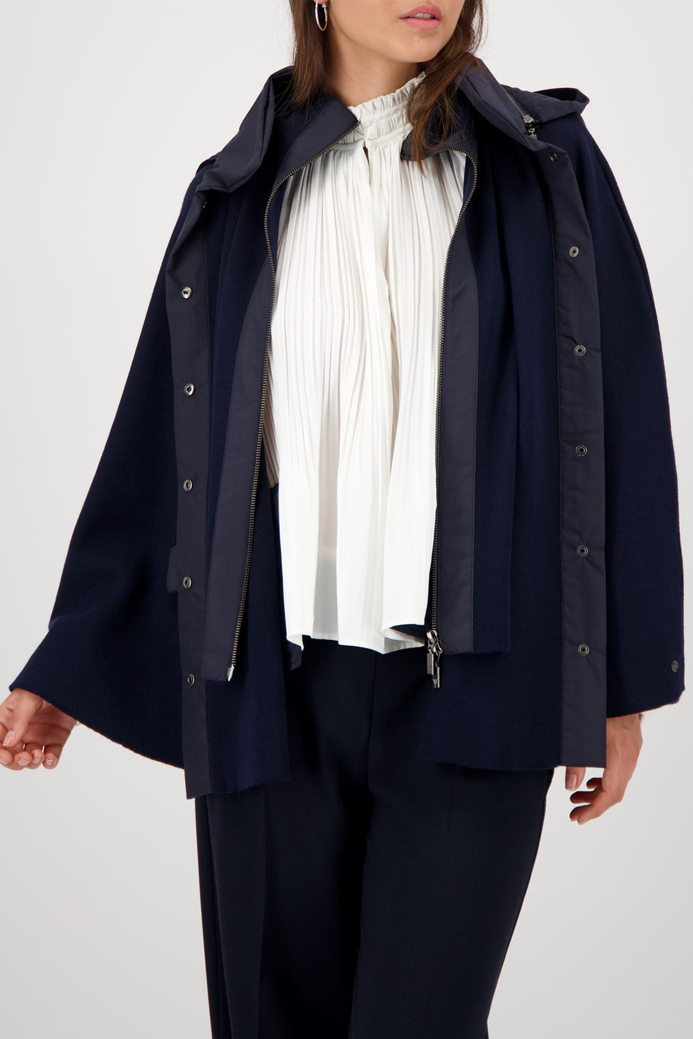 Person wearing a navy raincoat over a white shirt and dark pants on a light gray background