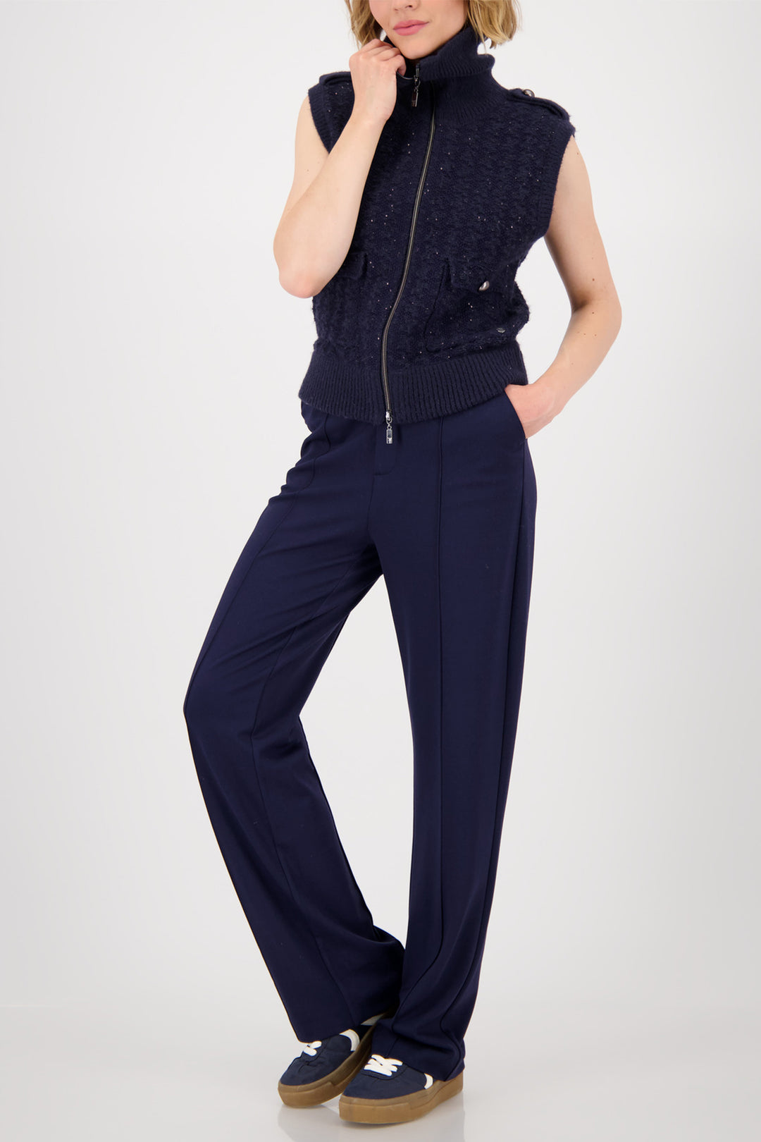 Person wearing a navy sleeveless knit top and pants on a white background