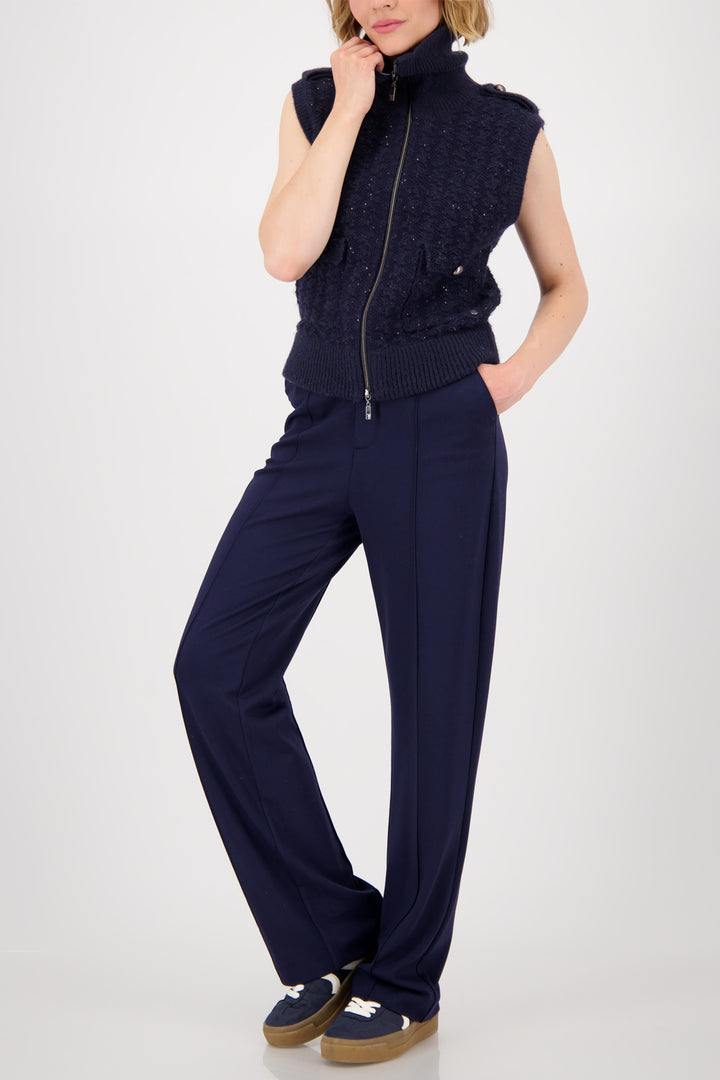 Person wearing a navy sleeveless knit top and pants on a white background