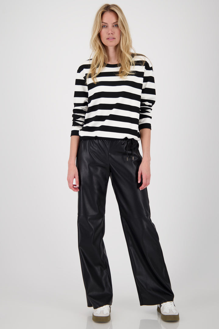 Woman wearing a black and white striped sweater and black pants on a white background