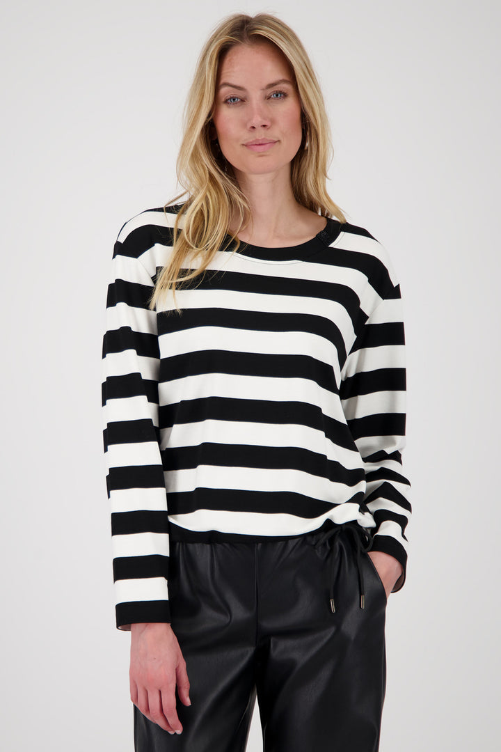 Woman wearing a black and white striped sweater with black pants on a white background