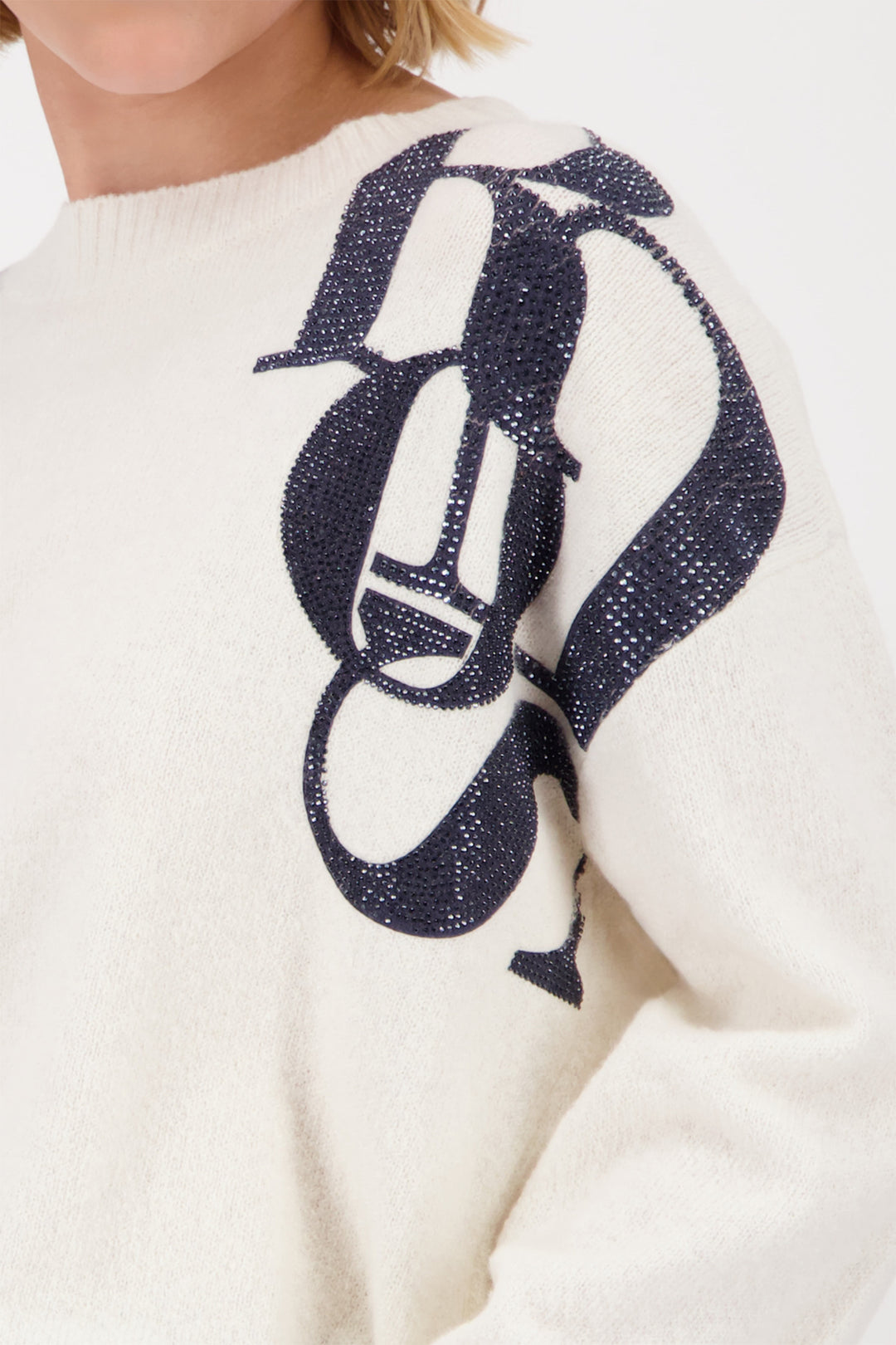 White sweater with a navy blue graphic design on the back