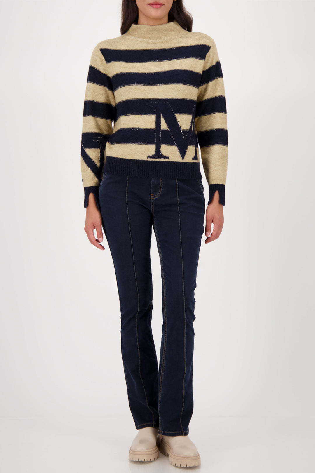 Person wearing a striped sweater and dark jeans on a white background