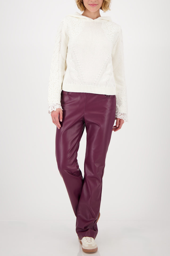 Person wearing a white sweater and purple pants on a white background