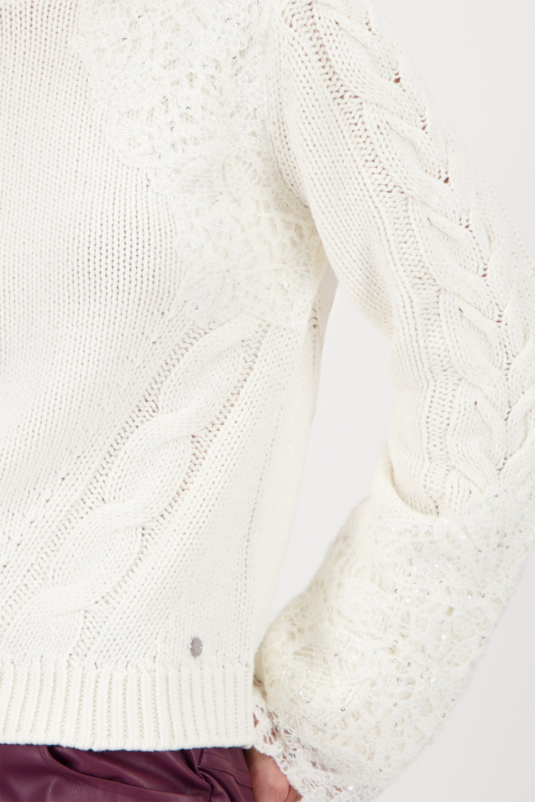 Close-up of a white cable-knit sweater on a white background