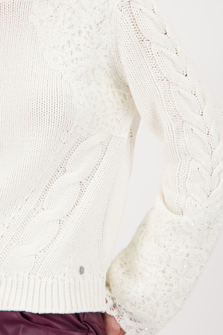 Close-up of a white cable-knit sweater on a white background