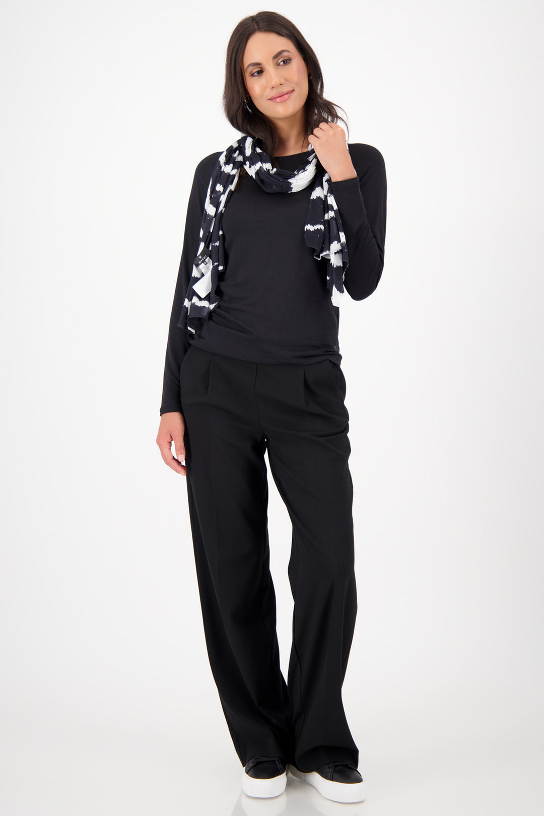 Woman wearing a black outfit with a patterned scarf on a white background