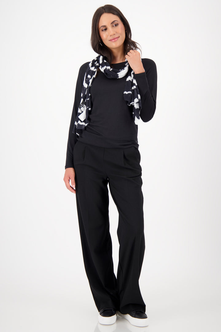 Woman wearing a black outfit with a patterned scarf on a white background