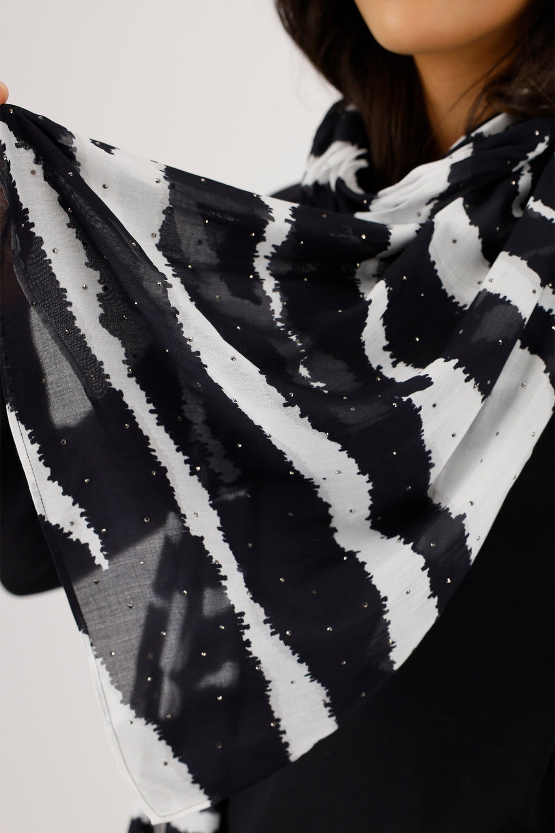 Black and white patterned scarf held by a person