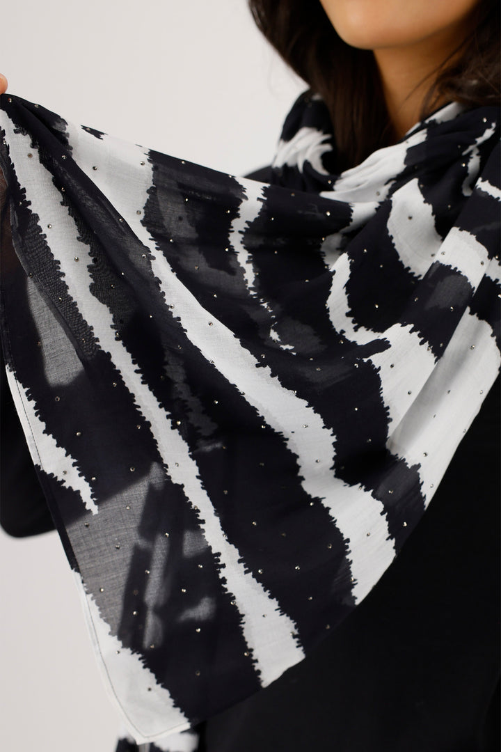 Black and white patterned scarf held by a person