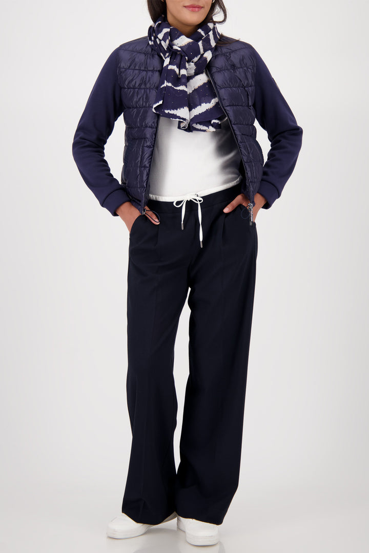 Person wearing a navy puffer jacket, white shirt, and black pants on a white background