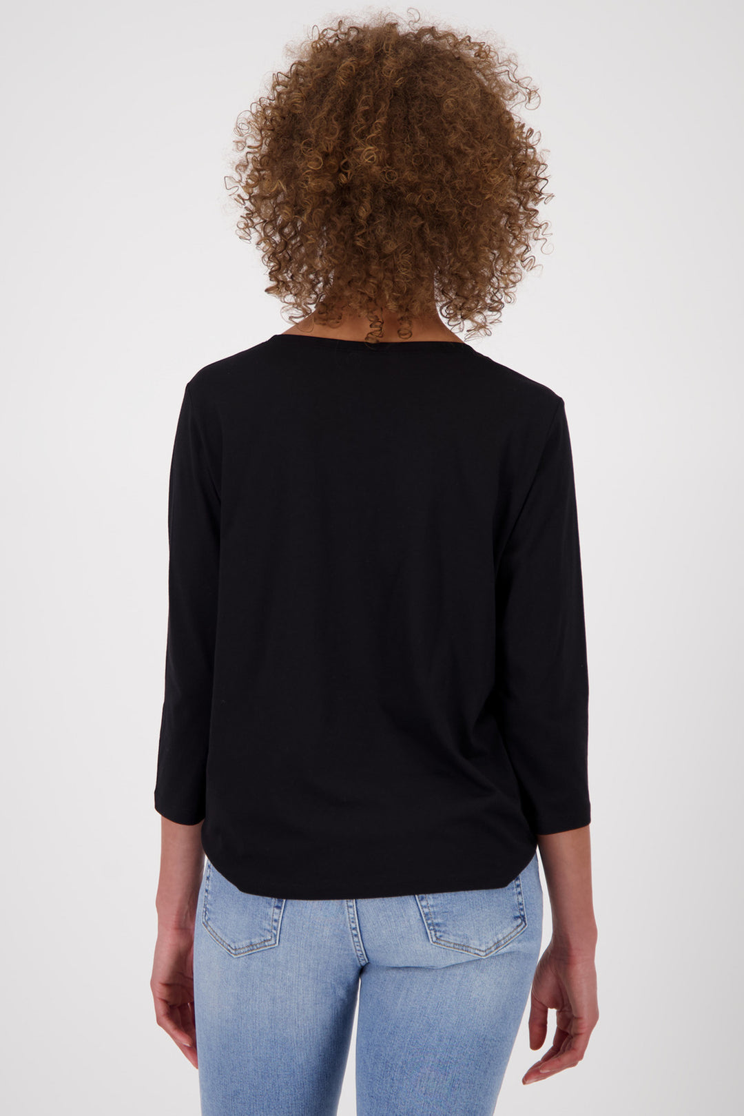 Person wearing a black long-sleeve top and light blue jeans on a white background