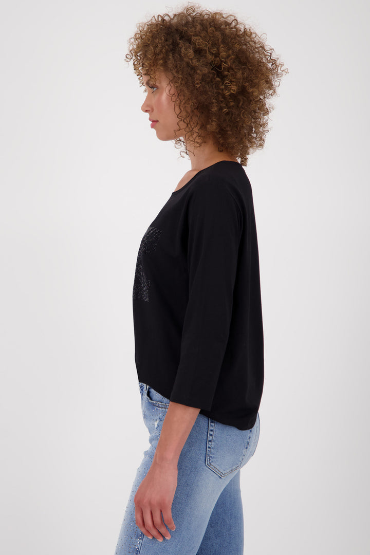Woman wearing a black top and blue jeans on a white background