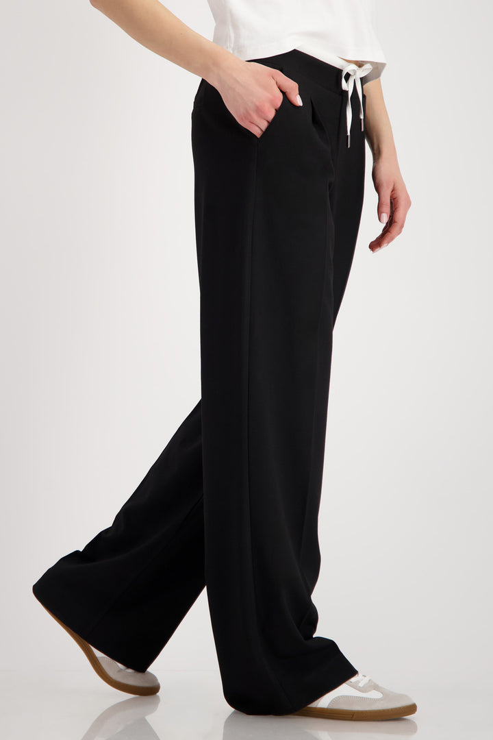 Person wearing black wide-leg pants on a white background