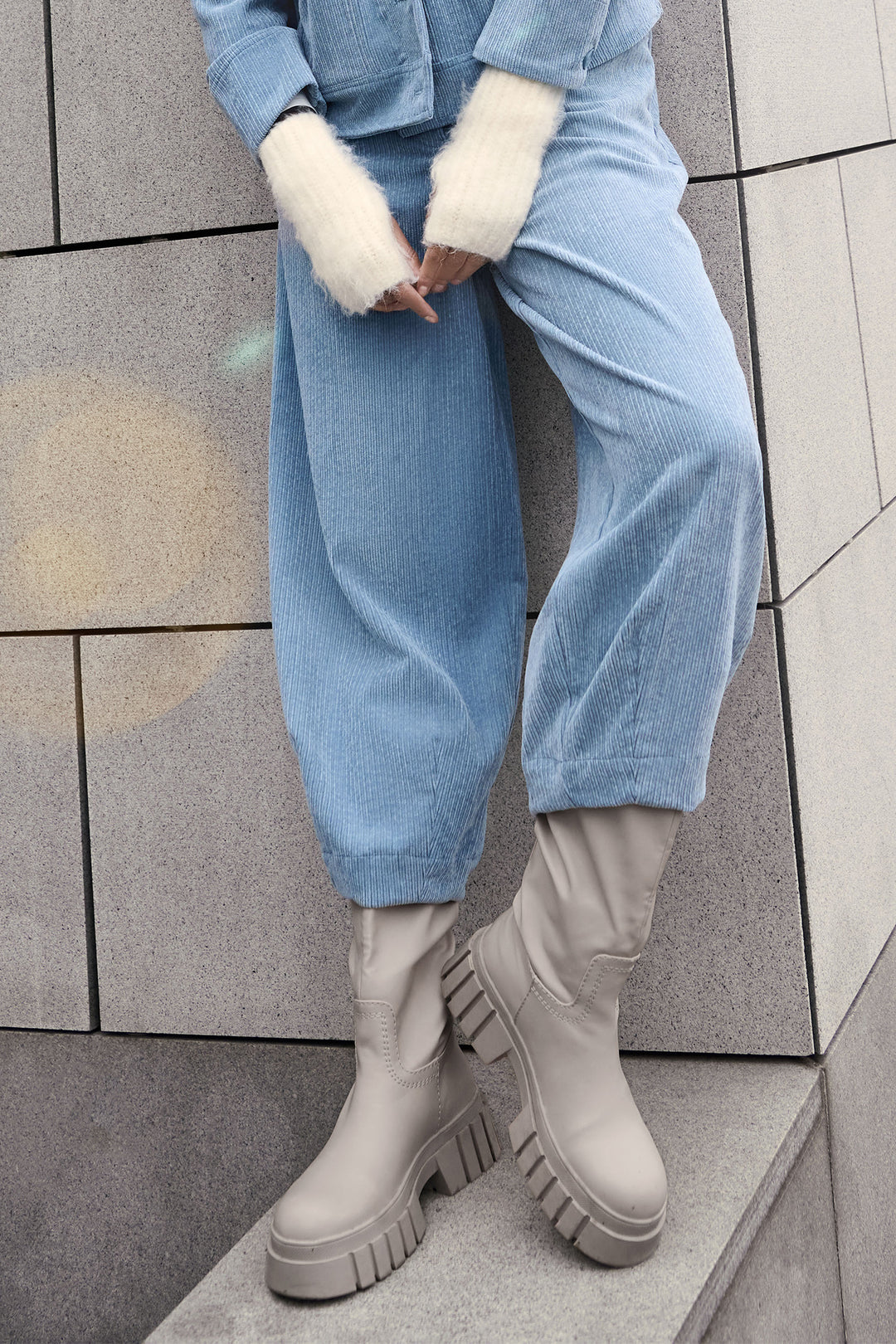 Person wearing blue pants and beige boots on a tiled floor