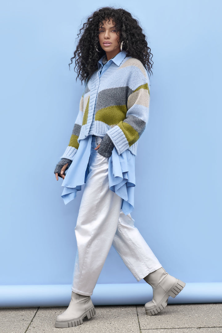 Person wearing a colourful sweater and silver jeans against a blue background