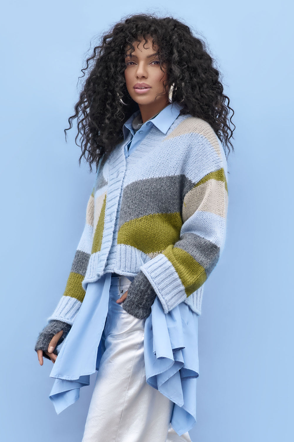 Woman wearing a colorful striped sweater over a light blue shirt against a light blue background