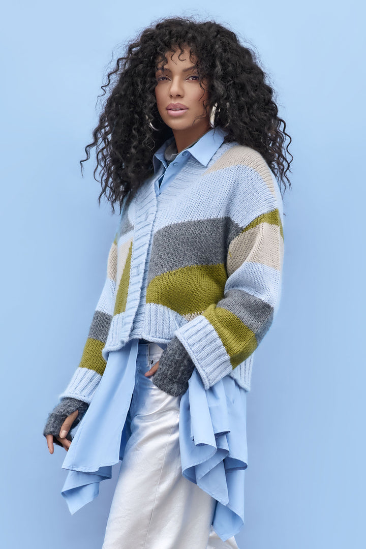 Woman wearing a colorful striped sweater over a light blue shirt against a light blue background