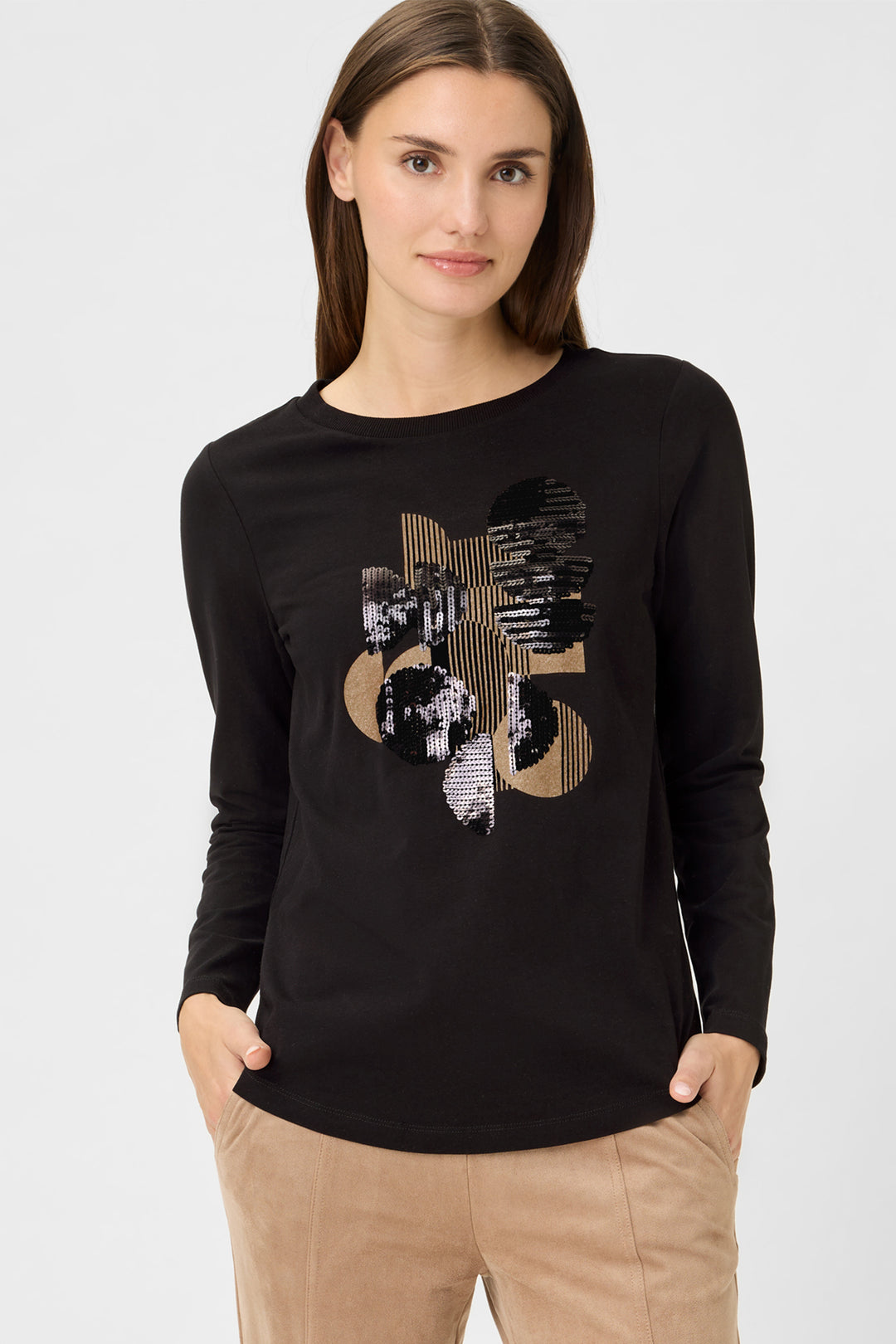 Woman wearing a black long-sleeve shirt with a decorative design on a white background