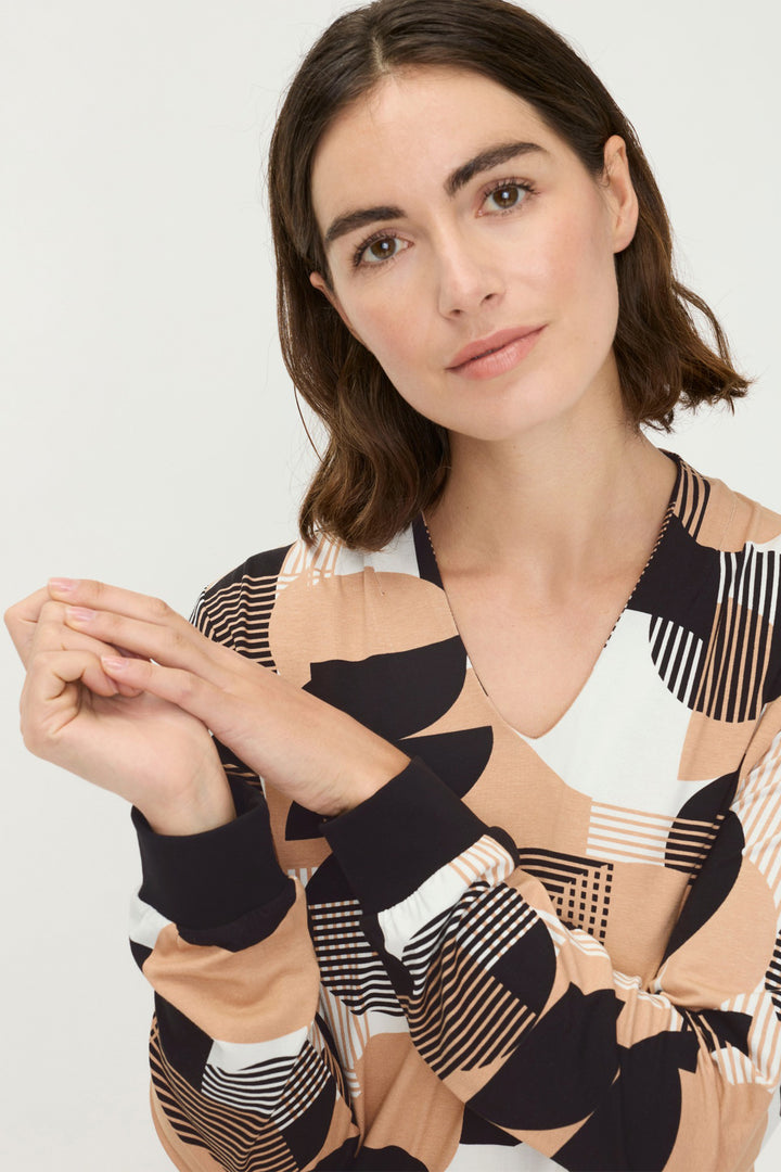 Woman wearing a patterned top with a neutral background