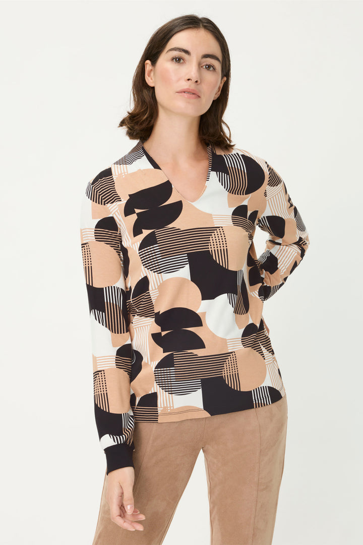 Woman wearing a patterned sweater with abstract designs on a plain background