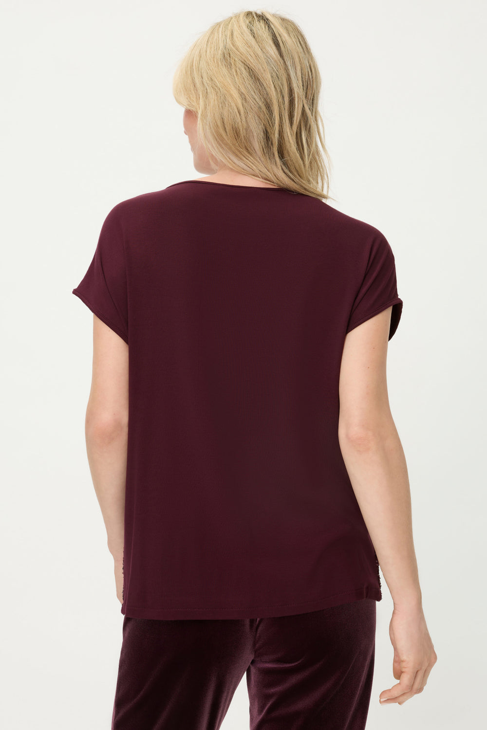 Person wearing a burgundy t-shirt and pants on a white background