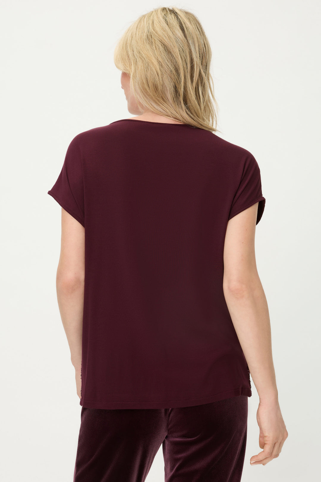 Person wearing a burgundy t-shirt and pants on a white background