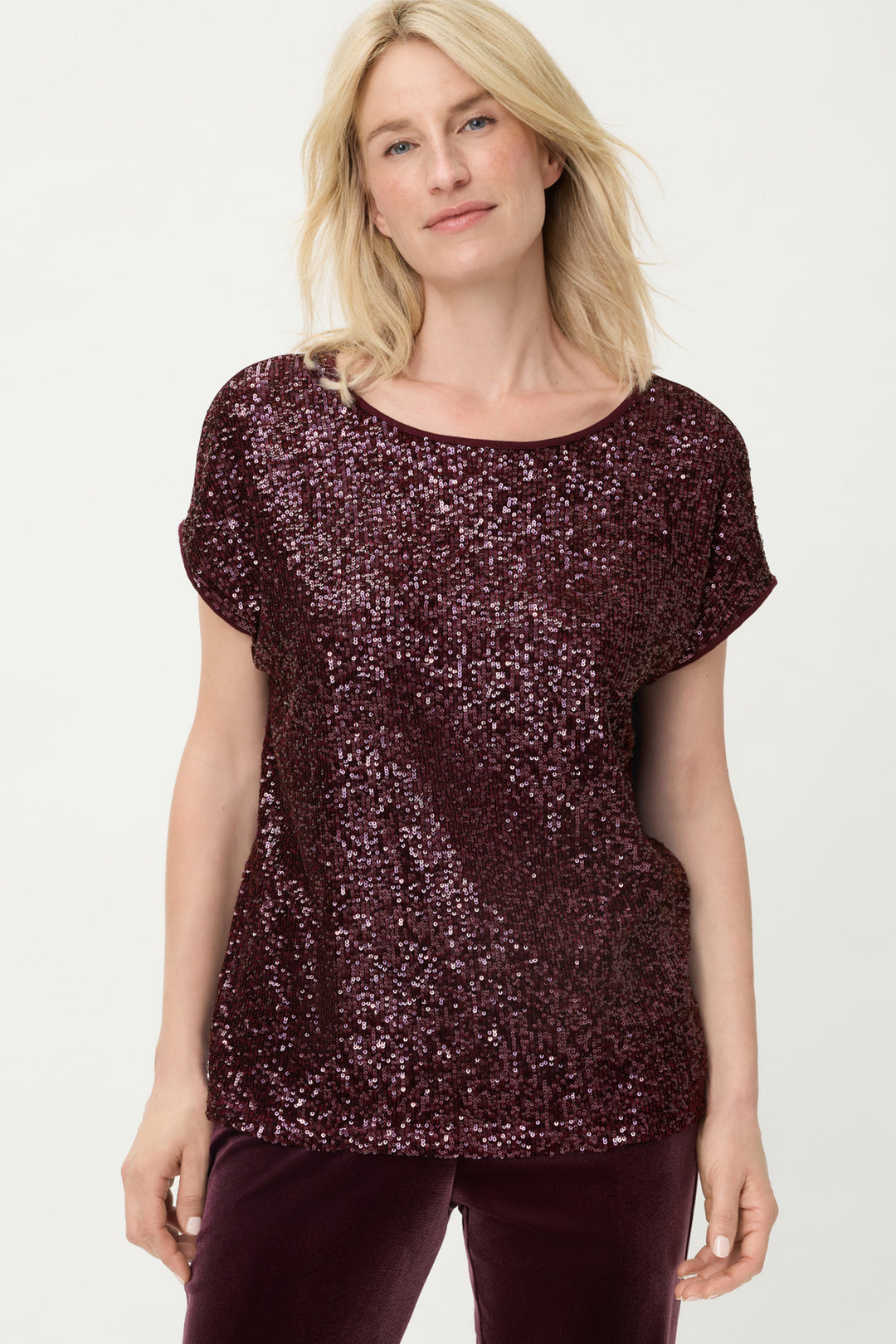 Woman wearing a sparkly burgundy top on a white background