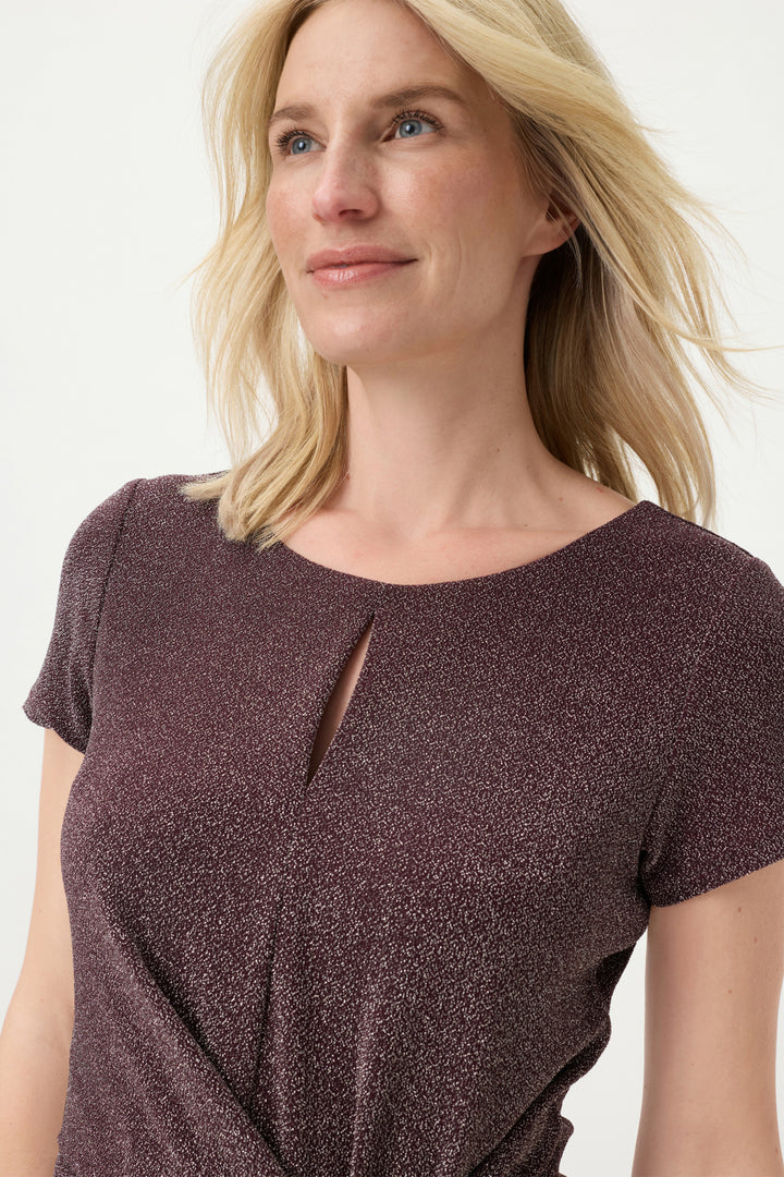 Woman wearing a dark wine short-sleeve top with a cutout detail on a white background