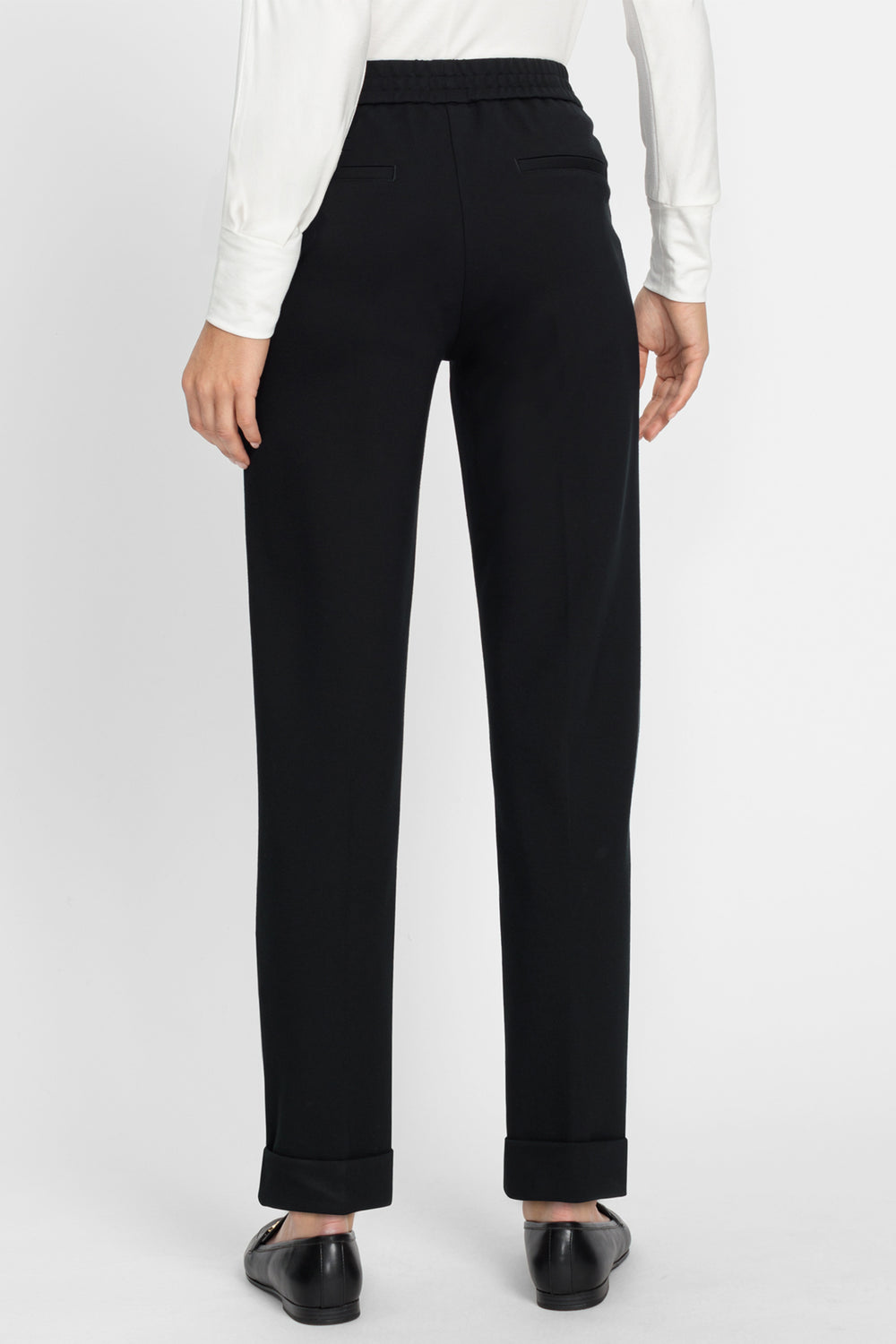 Black pants worn with a white shirt on a plain background