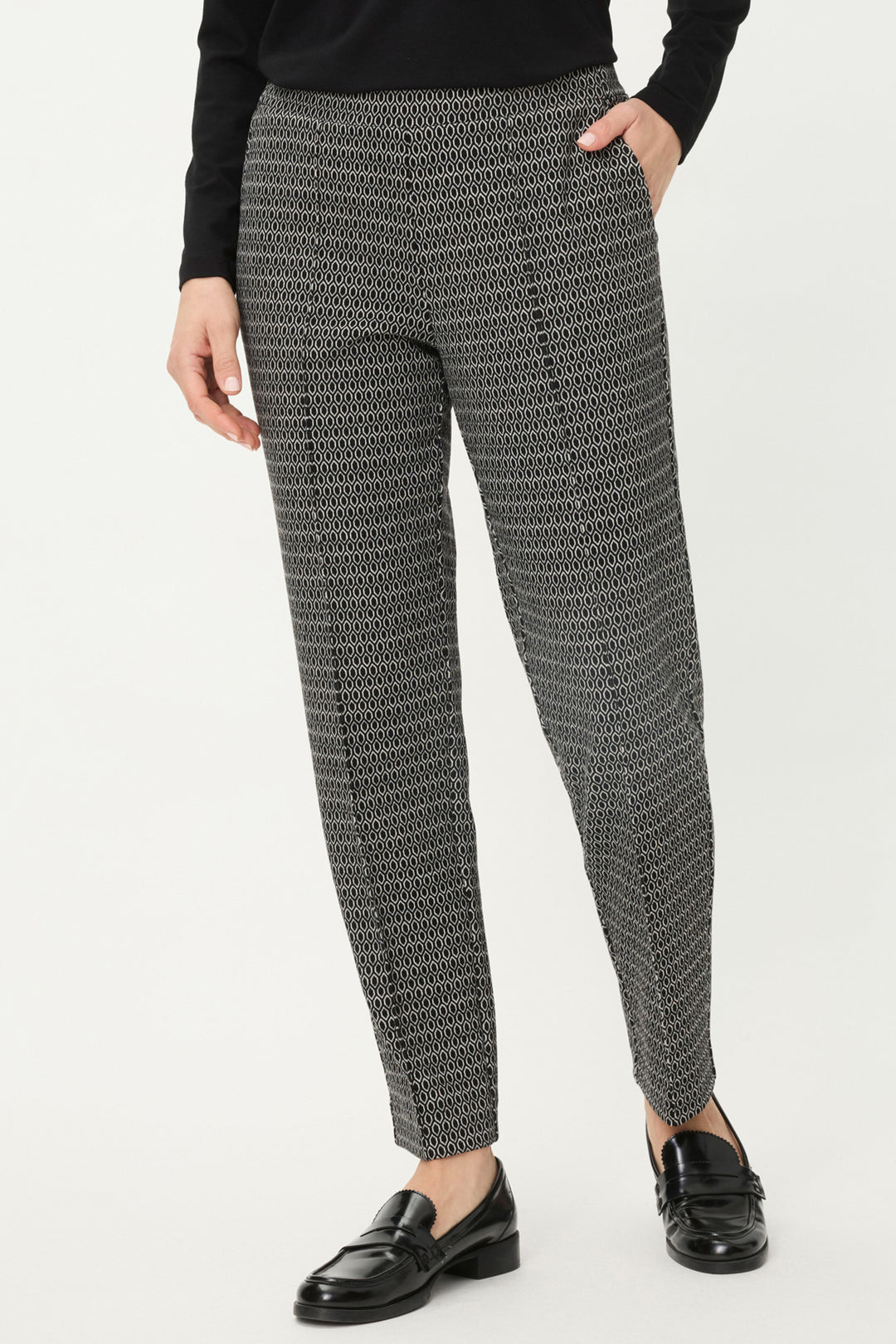 Person wearing black and white patterned pants on a white background
