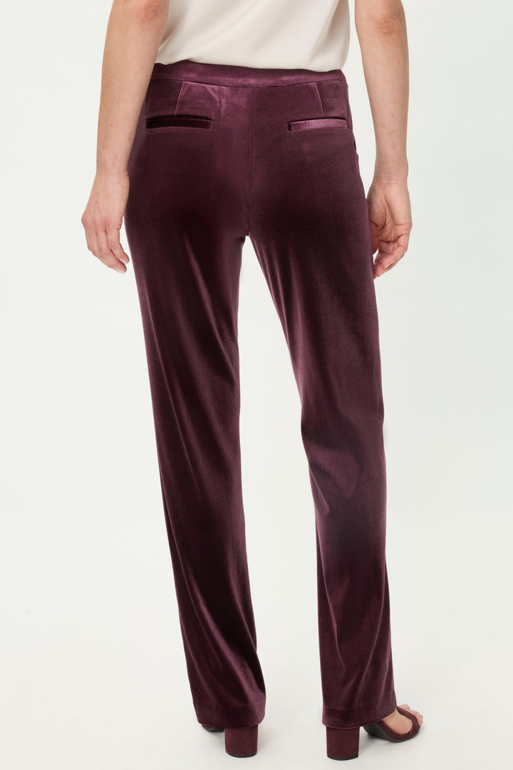 Dark wine velvet pants worn by a person on a white background