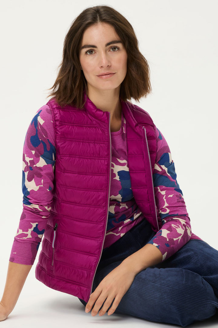 Woman wearing a pink puffer vest with floral sleeves on a white background