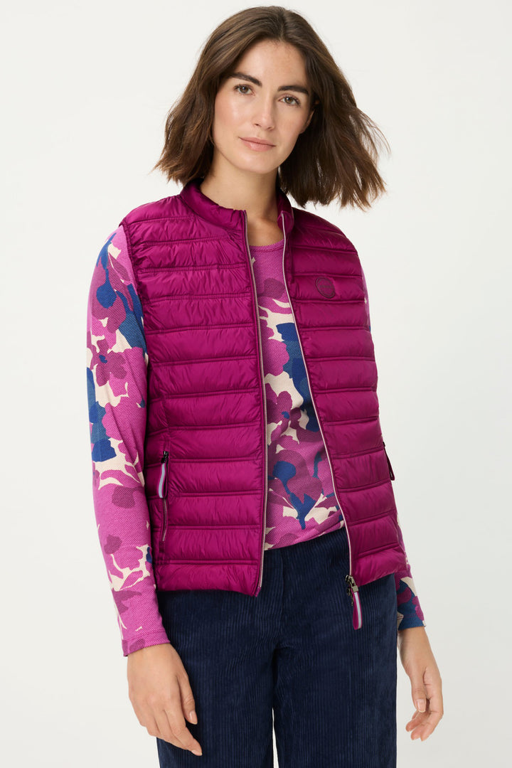 Woman wearing a pink puffer jacket with colorful sleeves on a white background