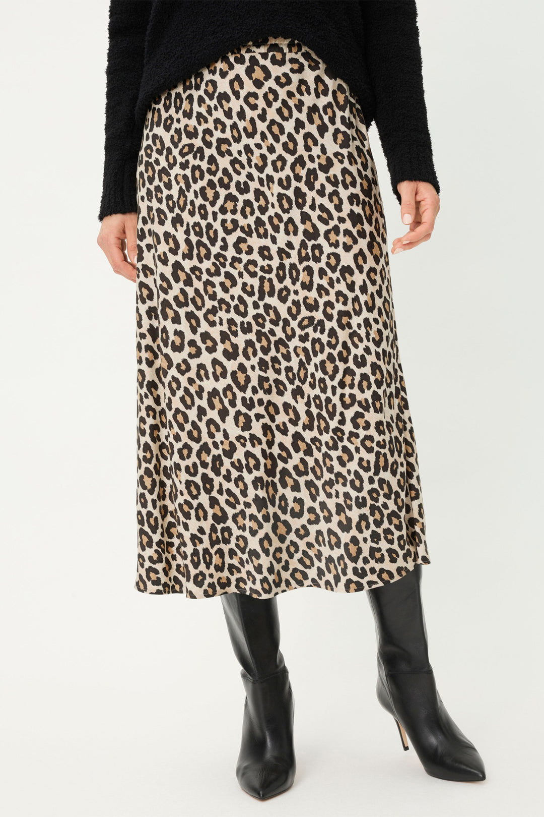 Person wearing a leopard print skirt with black boots on a white background