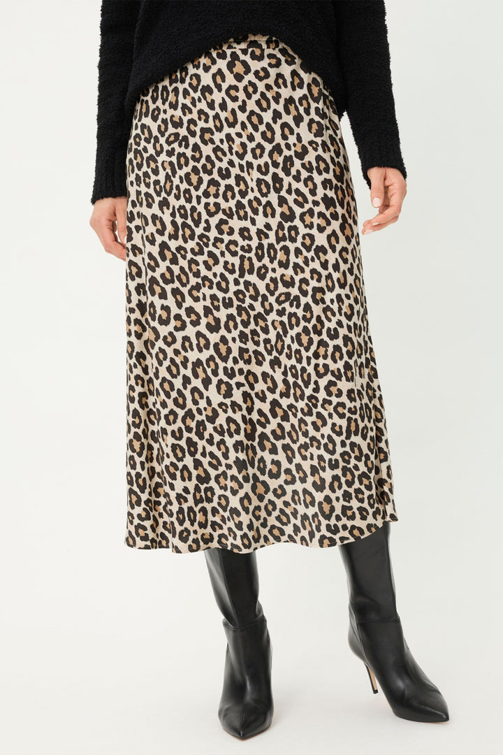 Person wearing a leopard print skirt with black boots on a white background