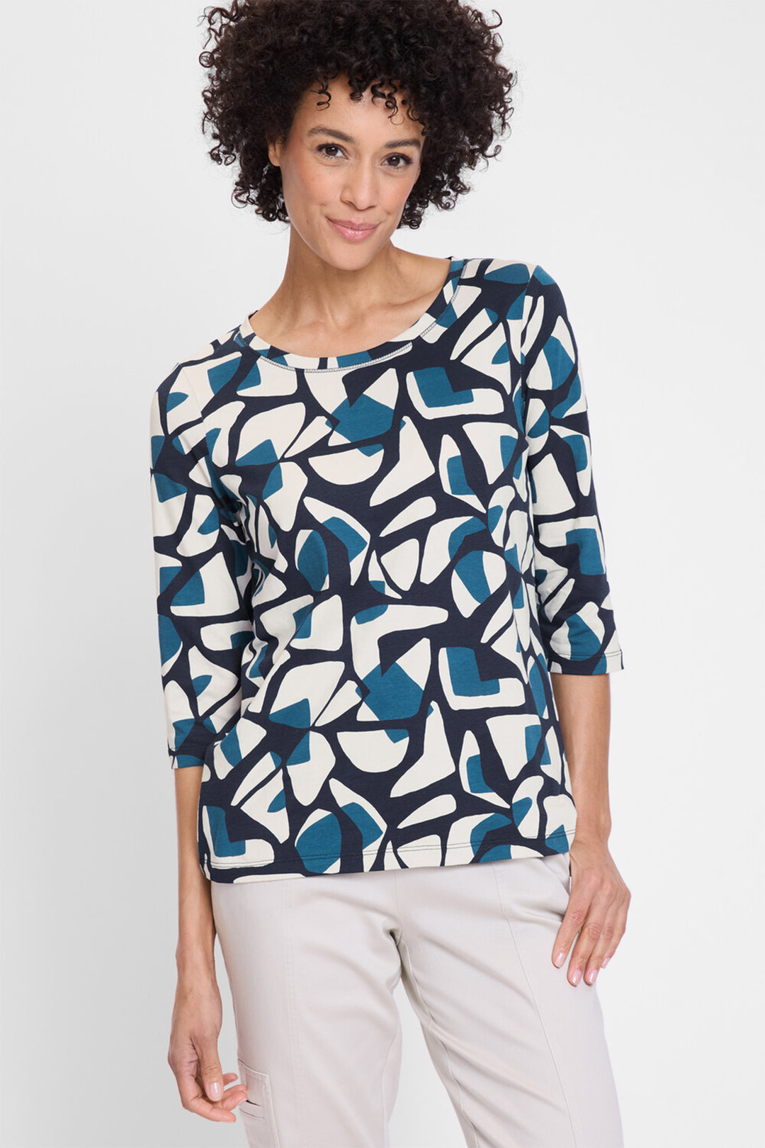 Woman wearing a patterned top with abstract design on a white background