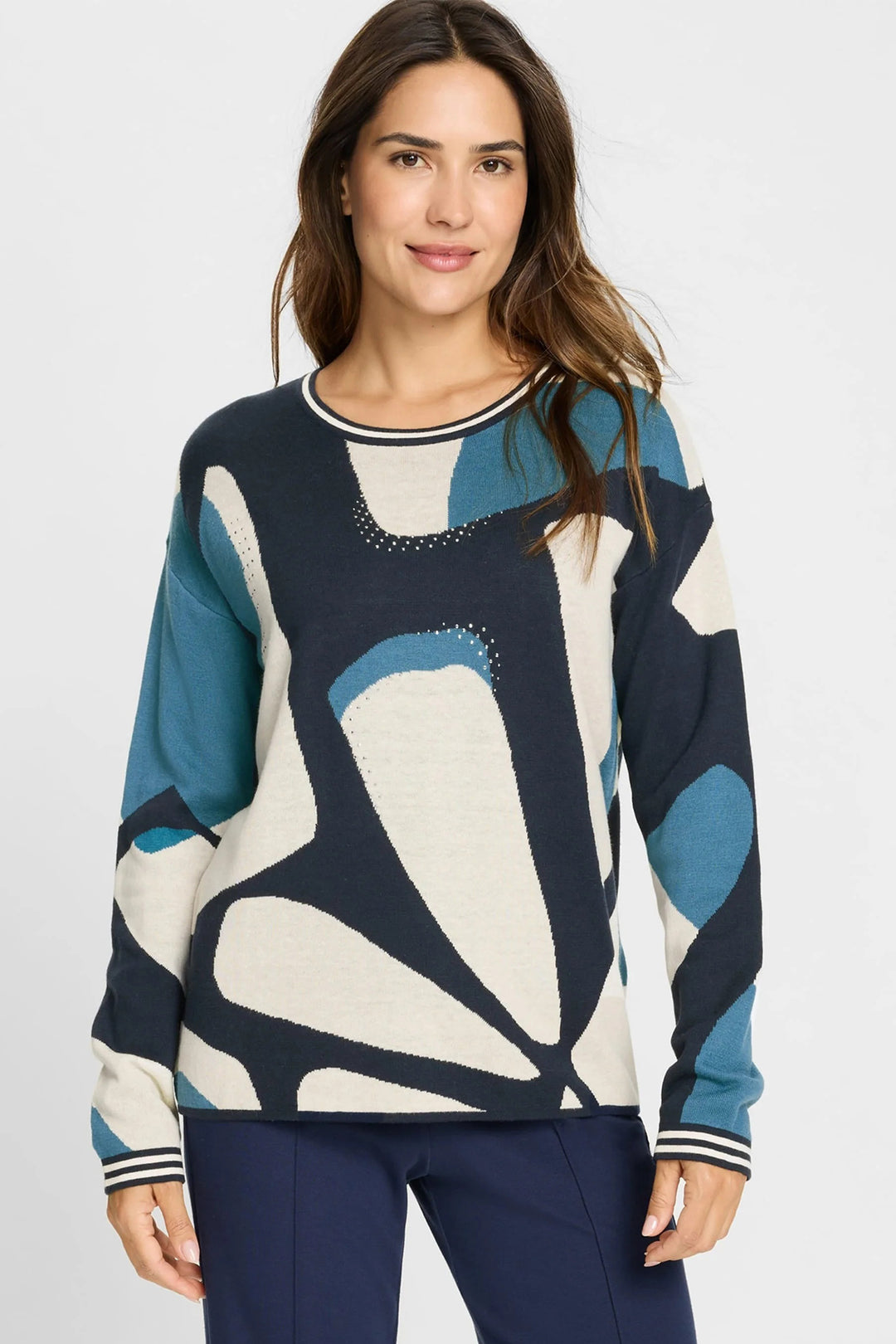 Woman wearing a patterned sweater with abstract design on a plain background