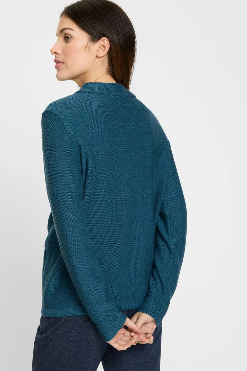 Woman wearing a teal long-sleeve shirt against a white background