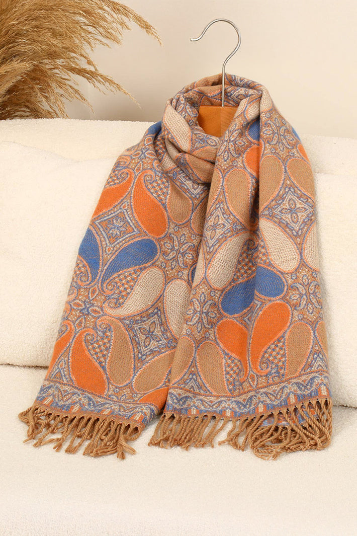 Patterned scarf with orange and blue design draped over a white surface