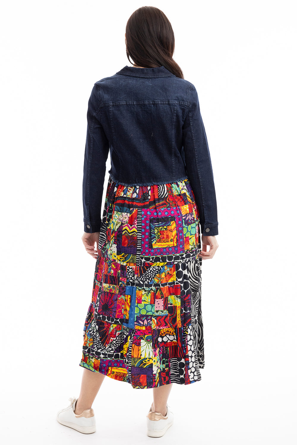 Woman wearing a colorful patterned skirt with a dark denim jacket on a white background