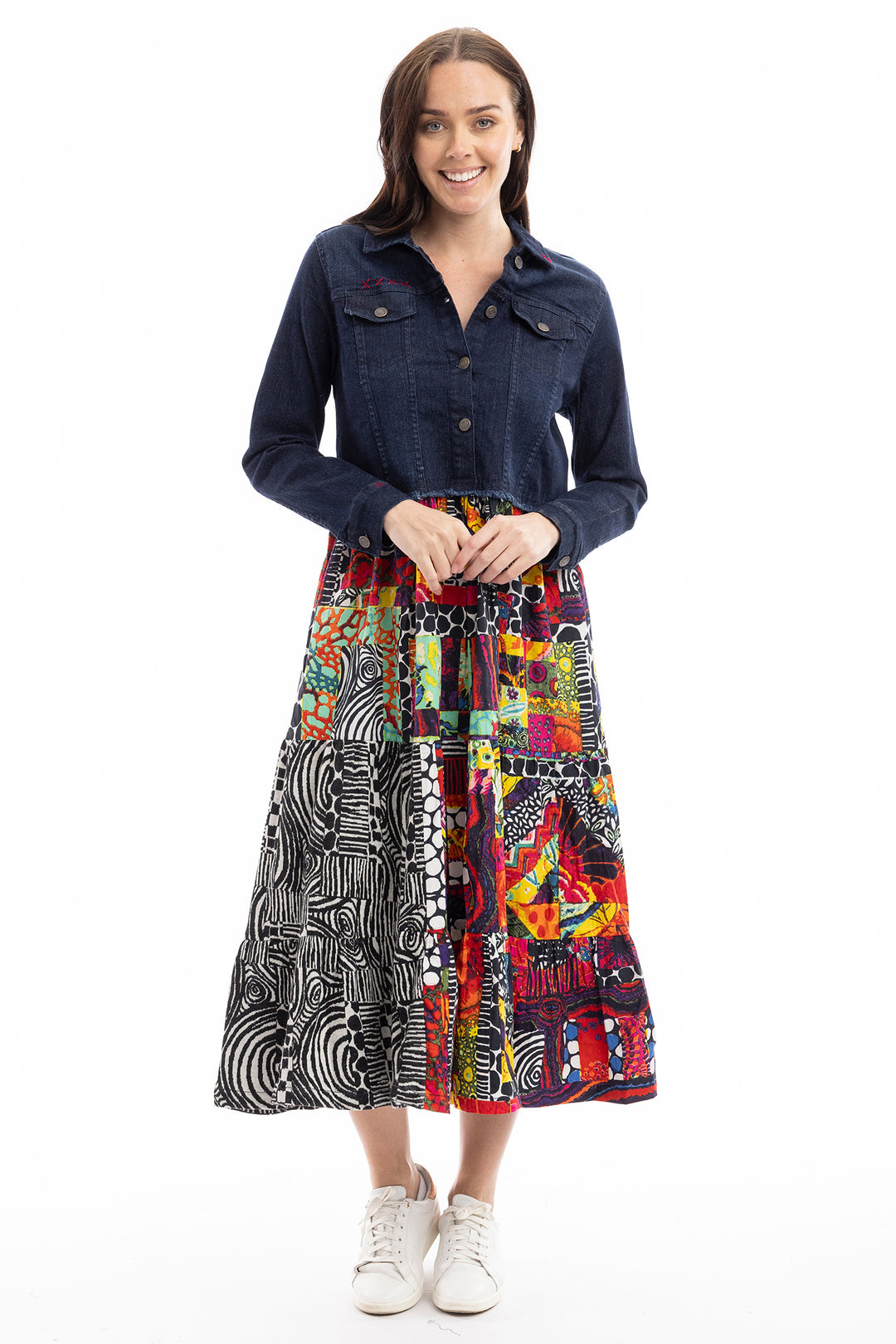Woman wearing a denim shirt and colorful patterned skirt on a white background