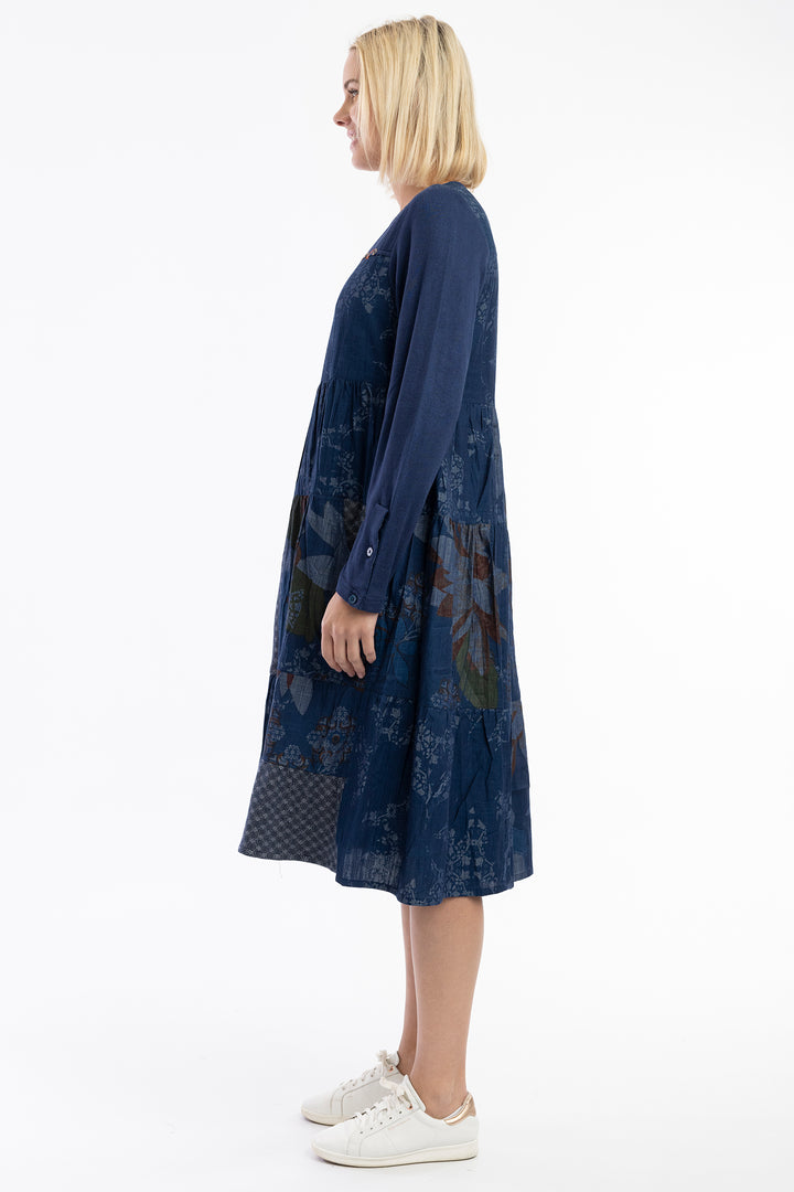 Woman wearing a blue dress with a patterned design on a white background