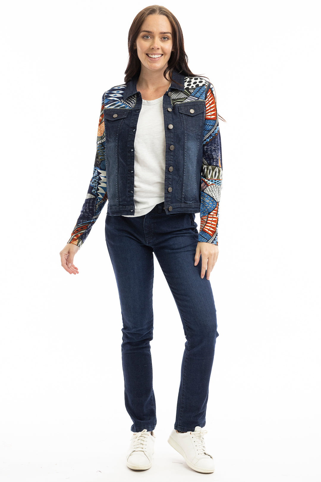 Woman wearing a colorful patchwork denim jacket on a white background