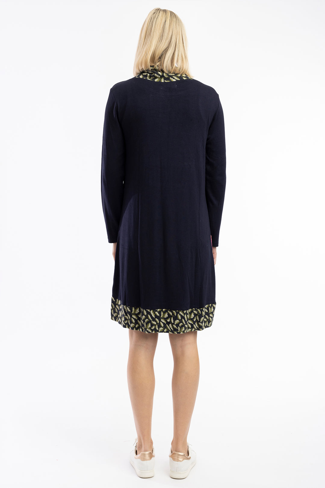 Woman wearing a navy dress with patterned hem on a white background