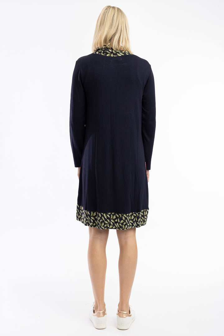 Woman wearing a navy dress with patterned hem on a white background